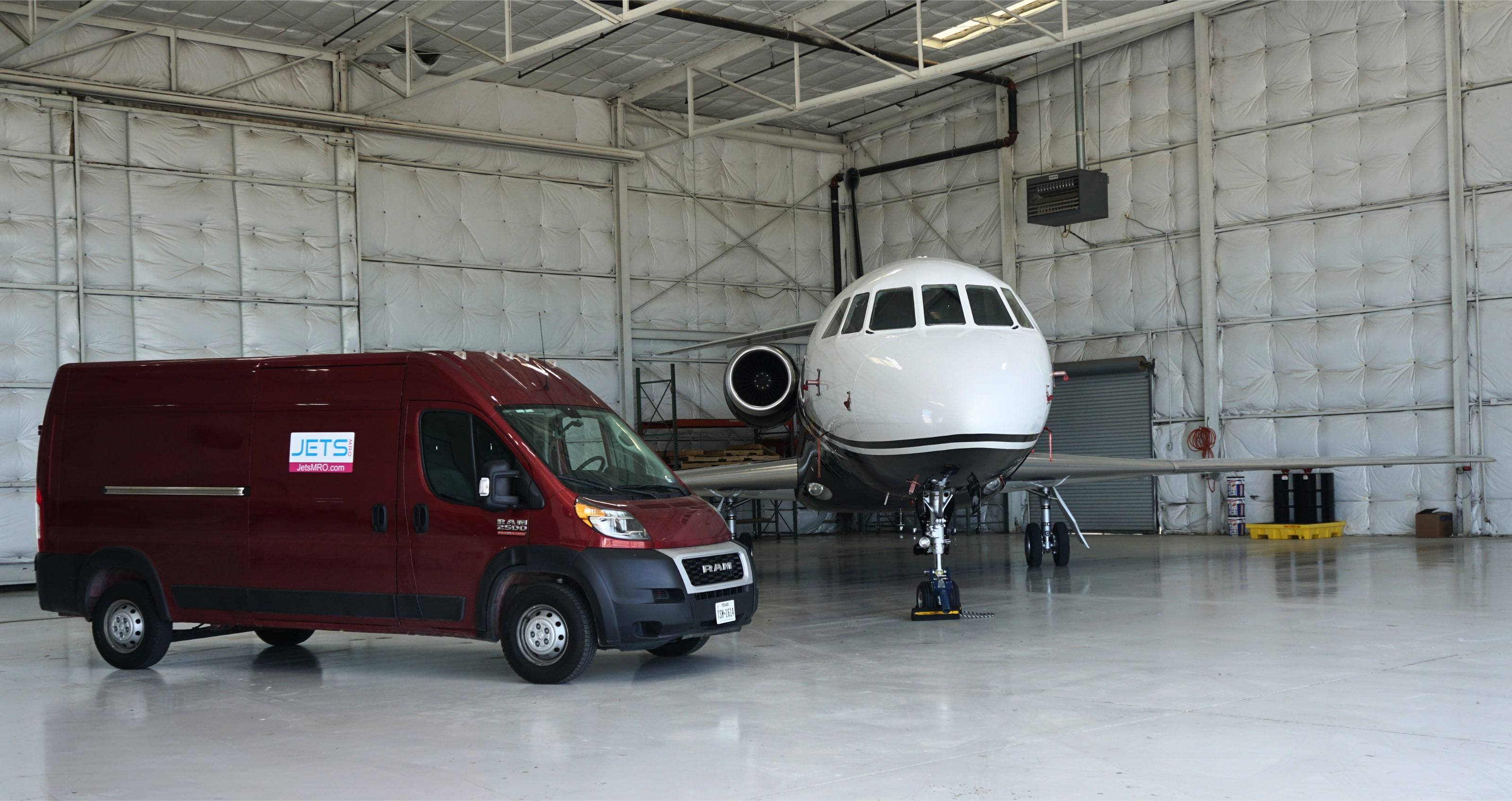 Maroon Jets MRO service van parked beside a business jet inside a hangar