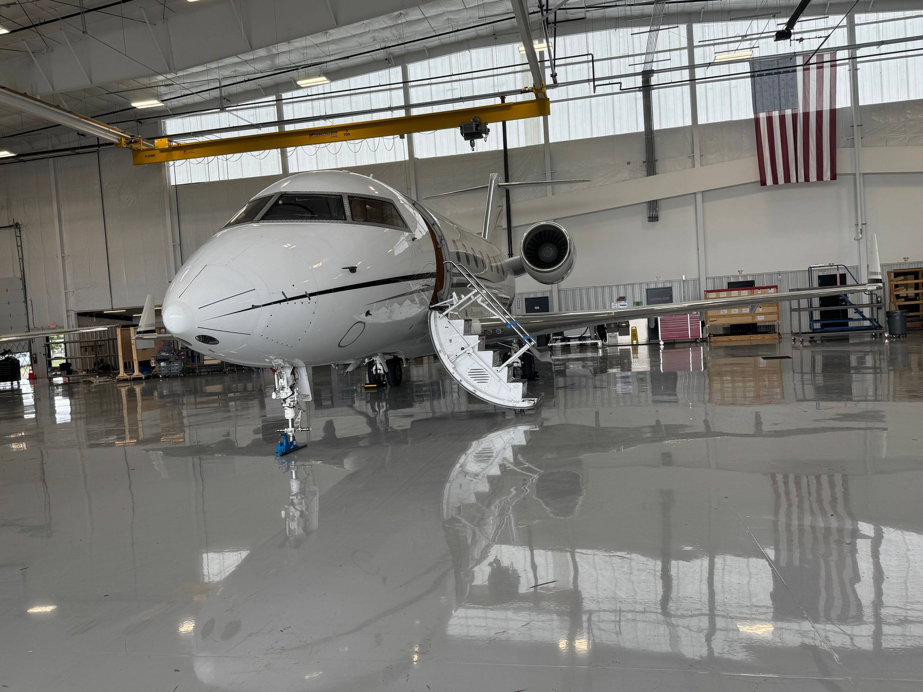 Bombardier Challenger 600-series with its airstair down on the polished hangar floor, US flag on the wall