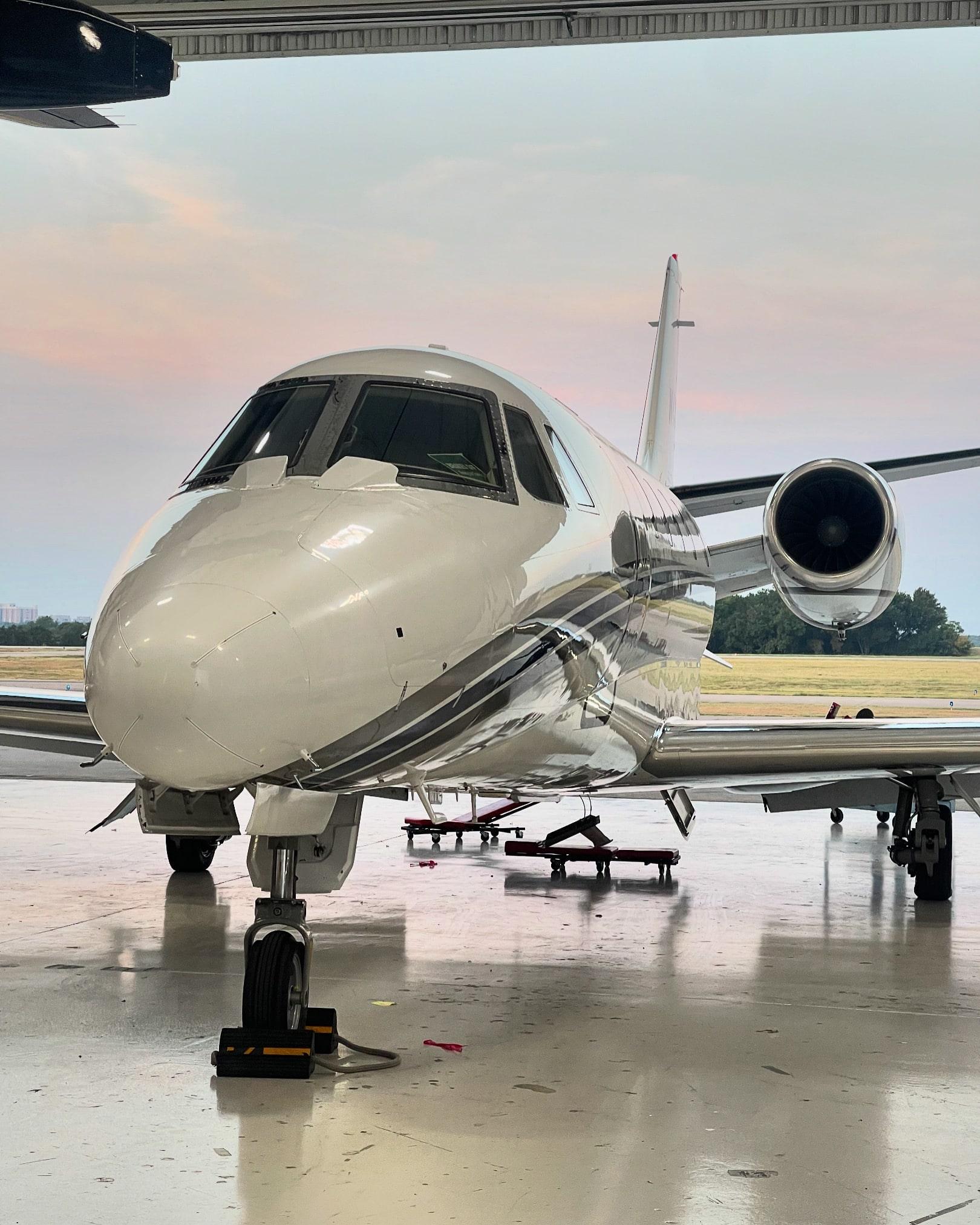 Cessna Citation parked at the open hangar door at dusk, pink sky and airfield behind