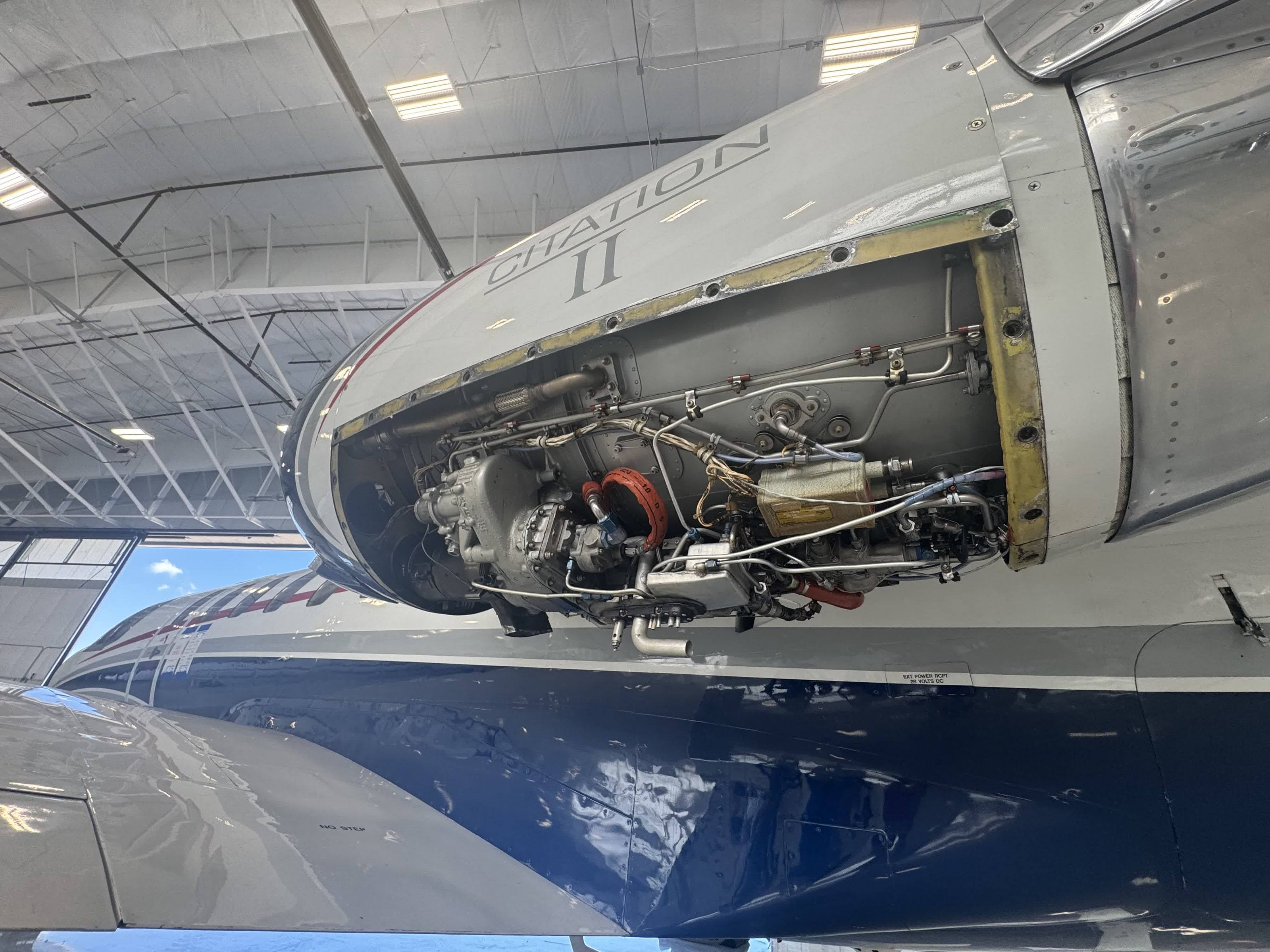Citation II engine with its cowling open, showing accessories, fuel and oil lines and wiring