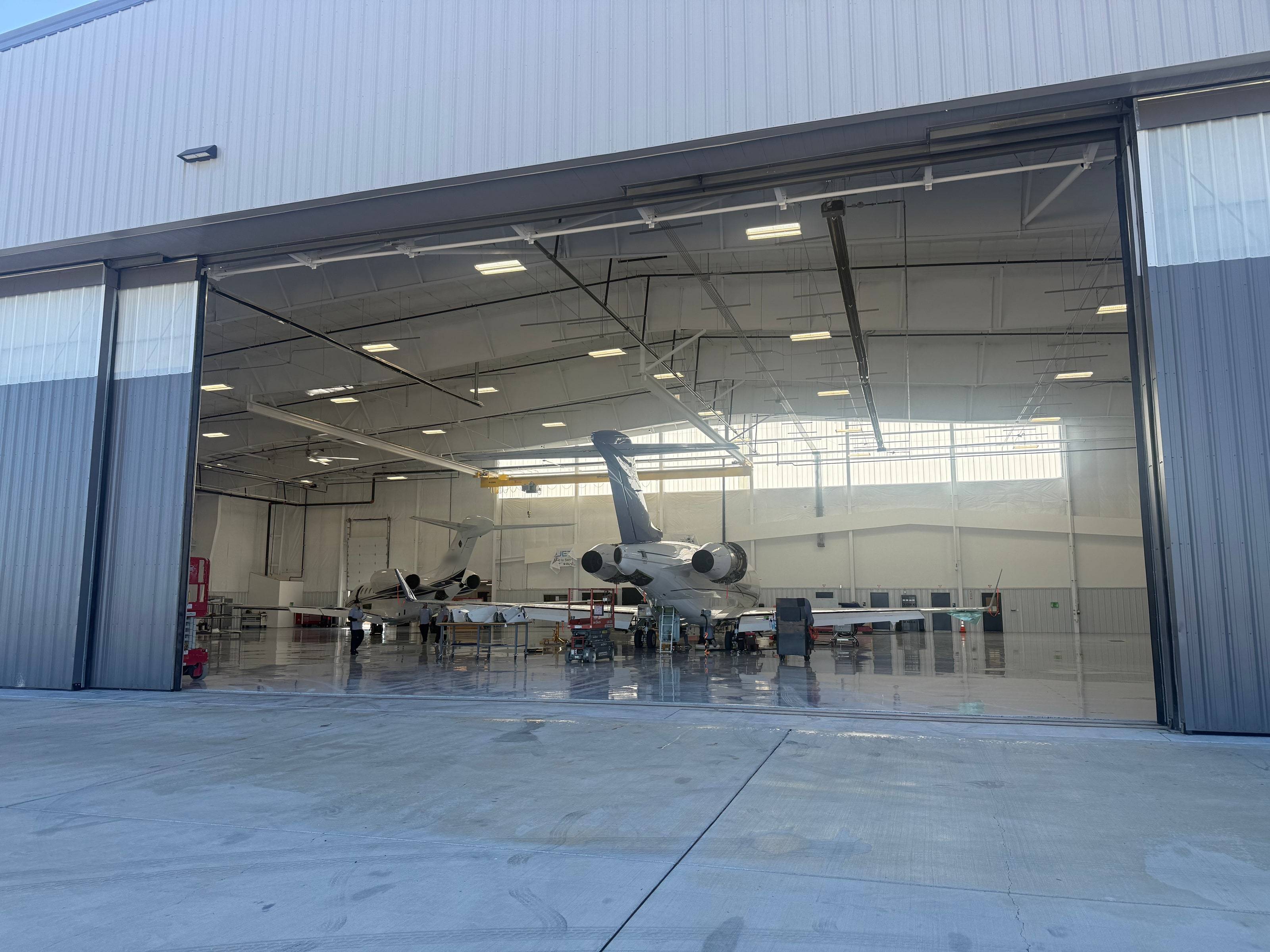 Jets MRO's Dallas Executive Airport hangar seen from the ramp, doors open, business jets and technicians inside