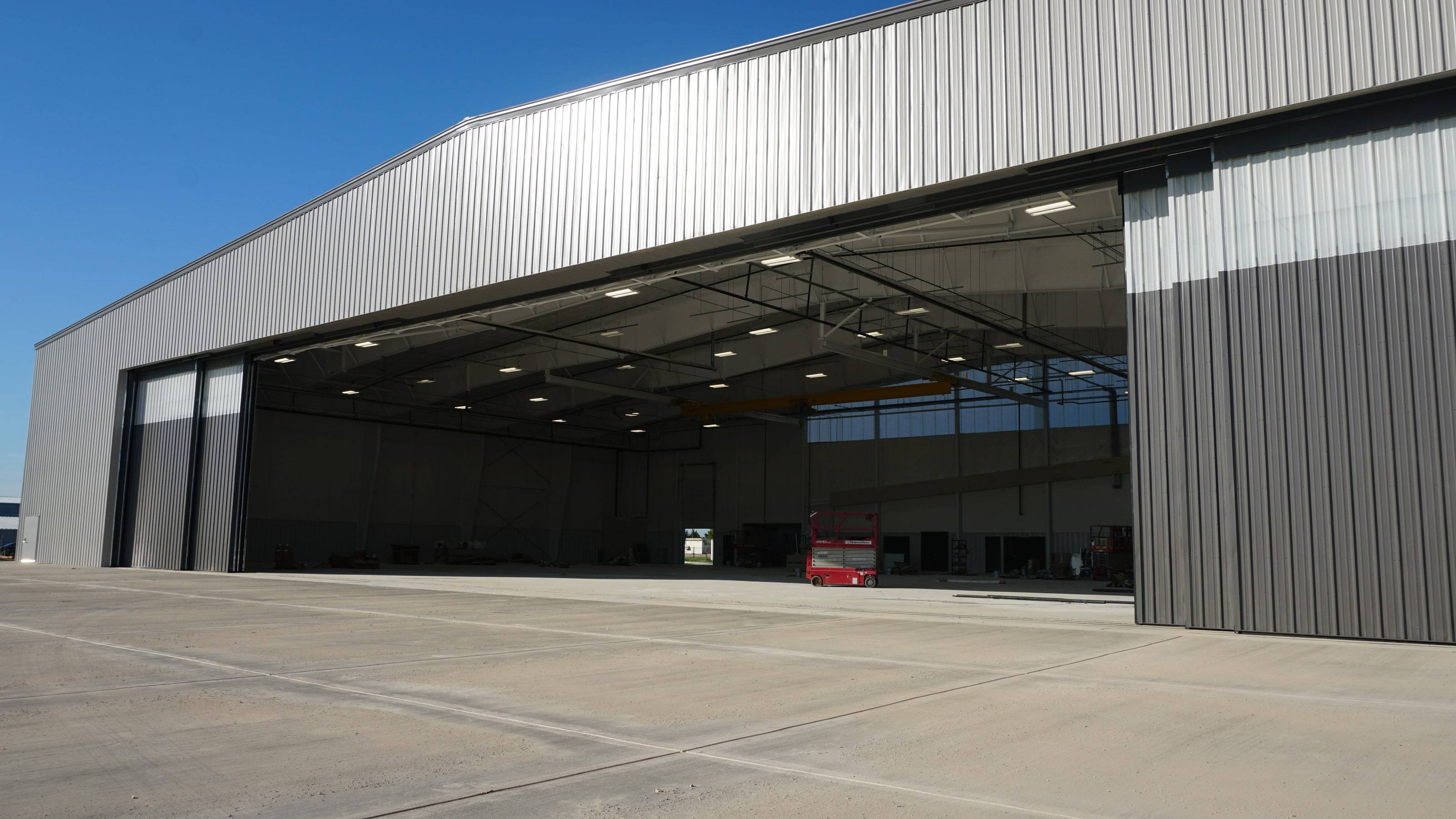 Newly built Jets MRO hangar at Dallas Executive Airport, doors open, interior empty, clear blue sky